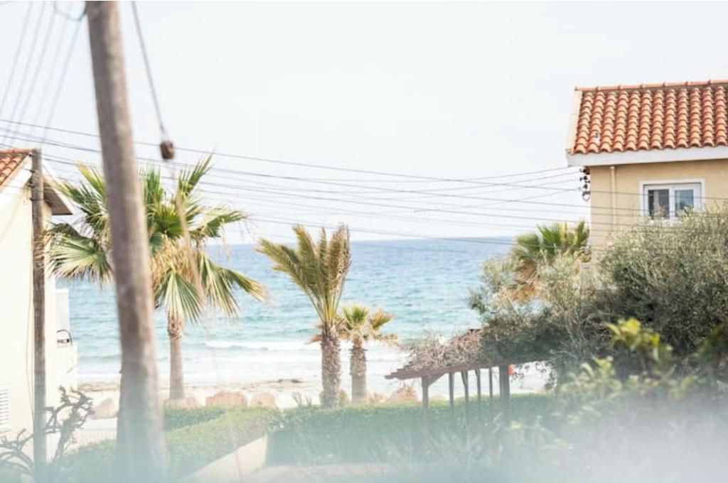 A coastal view with a building, palm trees, and the sea.