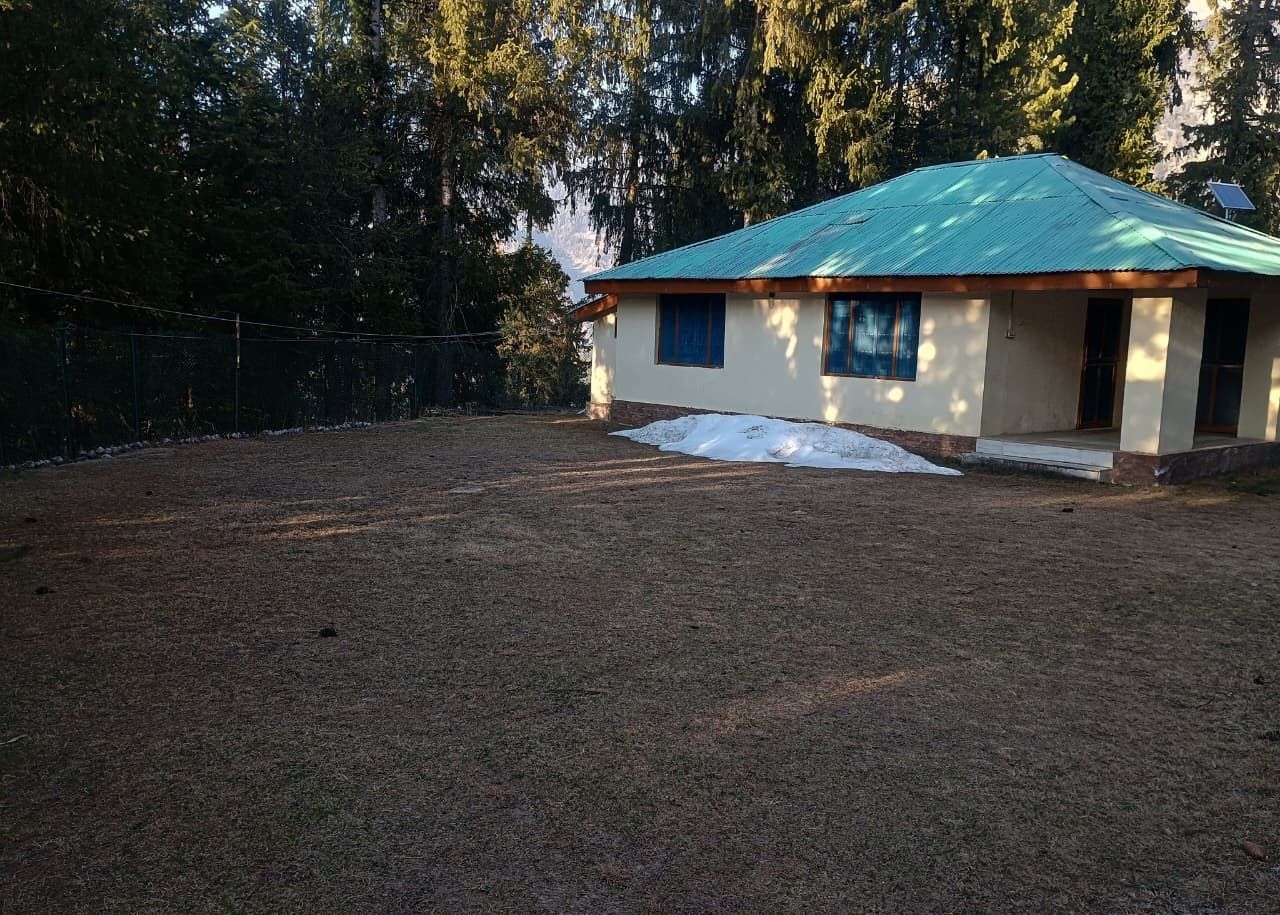 Una casa con techo verde, patio cercado y una zona con nieve.