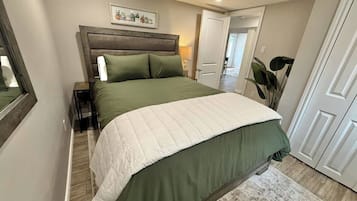 Ein Schlafzimmer mit einem Bett, Nachttischen, einem Wandregal mit Blumentöpfen und einer Tür zu einem anderen Raum.