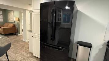 Eine moderne Küche mit einem schwarzen Kühlschrank, einer Mülltonne und einem Essbereich mit einem Stuhl.