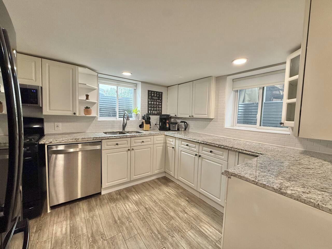A modern kitchen with white cabinets, stainless steel appliances, and a granite countertop.