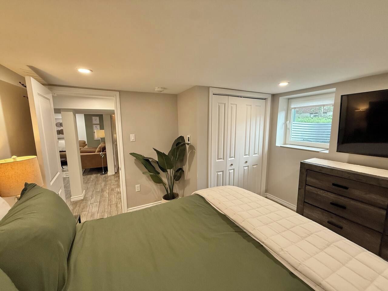 A bedroom with a bed, a dresser, a television, and a window.