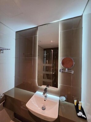 Ein modernes Badezimmer mit großem Spiegel, Waschbecken und Duschbereich.