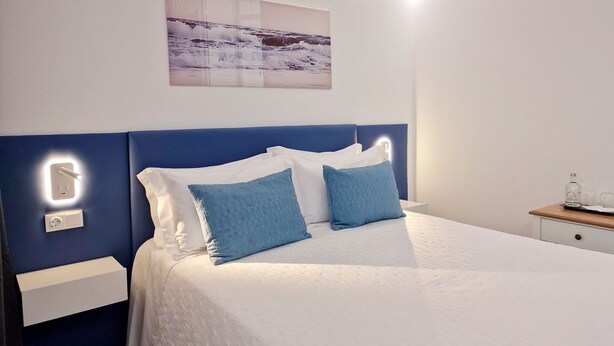 Un dormitorio moderno con una cama, mesitas de noche y una lámpara fijada a la pared.