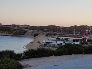 A coastal hotel with a beach view, a road, and a hilly landscape. - Golfinho Azul (Odemira)