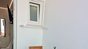 Una mesa de madera con sillas, un ventanal pequeño y una planta en maceta.