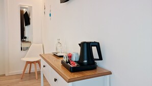 Una kitchenette pequeña con cafetera, una silla, un espejo y una encimera de madera.
