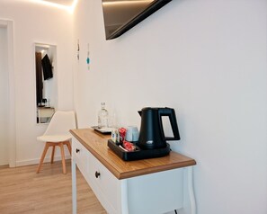 A small kitchenette with a coffee maker, a chair, a mirror, and a wooden counter. - Golfinho Azul (Odemira)