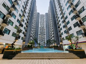 A high-rise residential building with multiple balconies, a central courtyard with a pool, and surrounding greenery. - The Jarrdin by Sewa Apart Bandung (COBLONG)