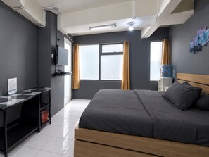 Una habitación de hotel moderna con cama, televisor, escritorio y ventana con cortinas.