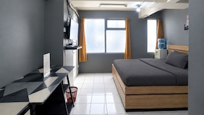Moderni hotellihuone, jossa on sänky, työpöytä ja ikkuna.