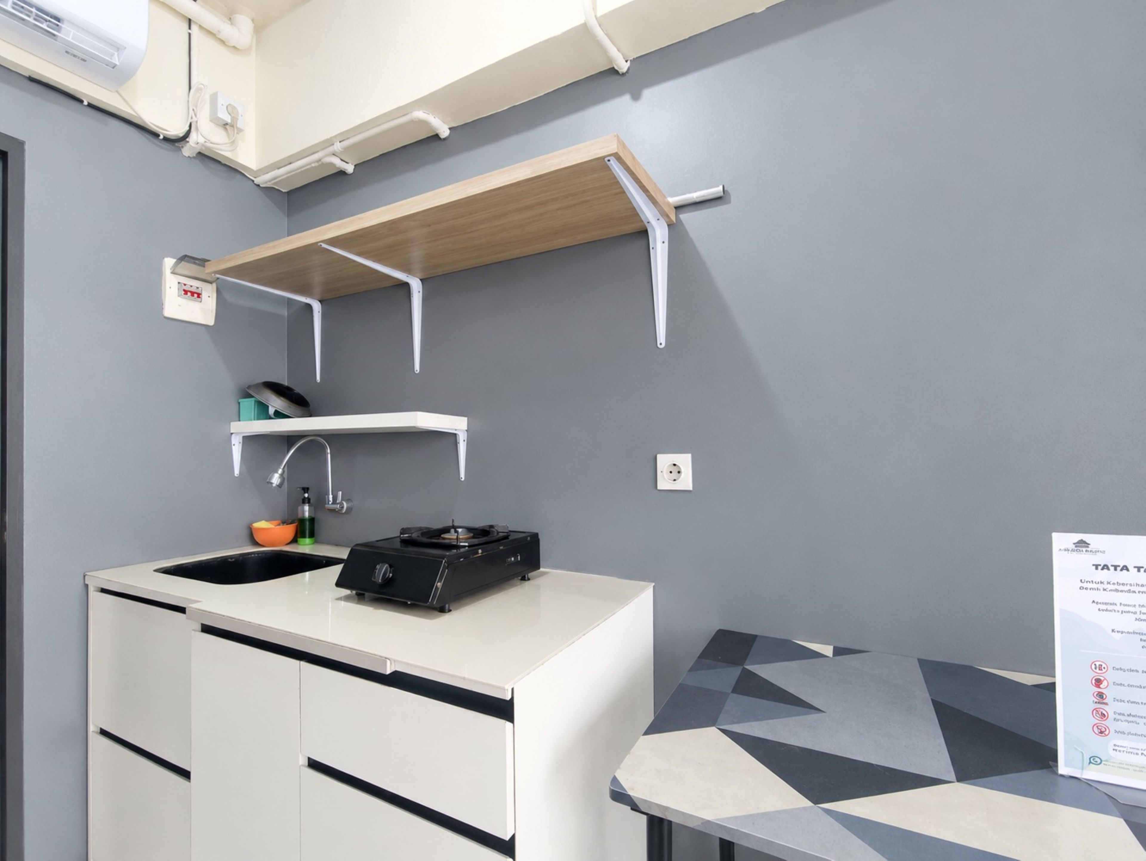 A kitchenette with a sink, stove, and storage cabinets.