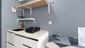 Pieni keittiönurkkaus, jossa on pesuallas, liesi ja säilytystilaa tarjoavat kaapit.
