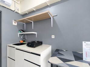 Una kitchenette con un lavamanos, estufa y armarios de almacenamiento.