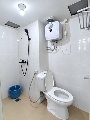 Un baño moderno con inodoro, ducha y un cubo azul.