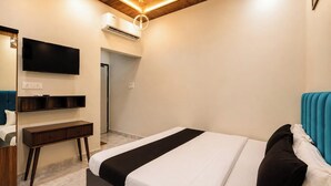 Una habitación de hotel moderna con cama, escritorio, televisor de pantalla plana y aire acondicionado.