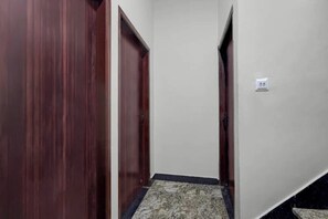 A hallway with wooden doors and a patterned carpet. - Divyam Grand (Varanasi)