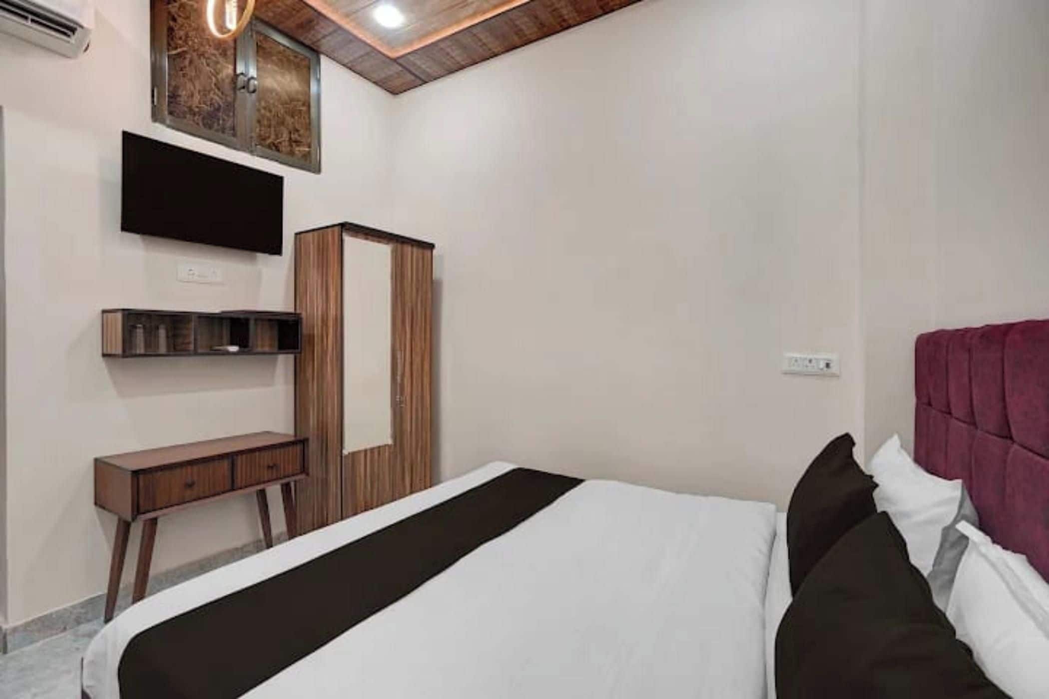 Une chambre à coucher comprenant un lit, une armoire, un bureau et un téléviseur fixé au mur.