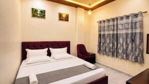 Un dormitorio con una cama grande, una silla, una mesita de noche y dos cuadros en la pared.