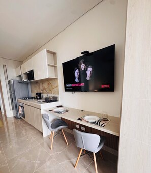 A modern kitchen with a dining area, a flat-screen TV mounted on the wall, and a kitchen island with seating. - Bello Horizonte Oceanfront Apartment Suite (Santa Marta)