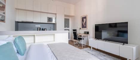 Una habitación de hotel moderna con cama, escritorio, televisión y kitchenette.