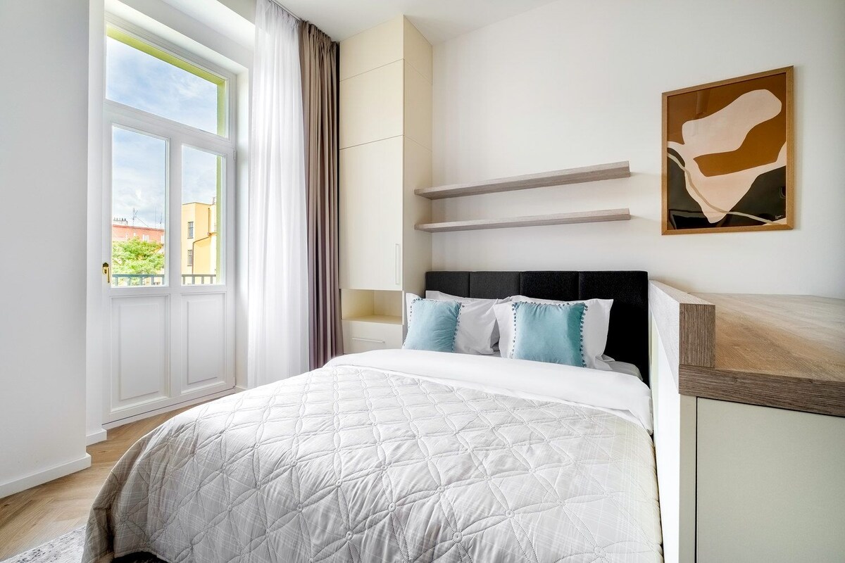A bedroom with a bed, a window, and a painting on the wall.