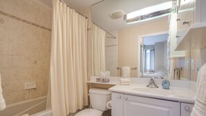 A bathroom with a bathtub, toilet, and sink, equipped with a mirror and towel rack.