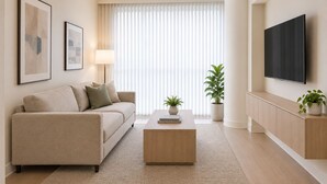 Ein modernes Wohnzimmer mit Sofa, Couchtisch und einem an der Wand befestigten Flachbildfernseher.