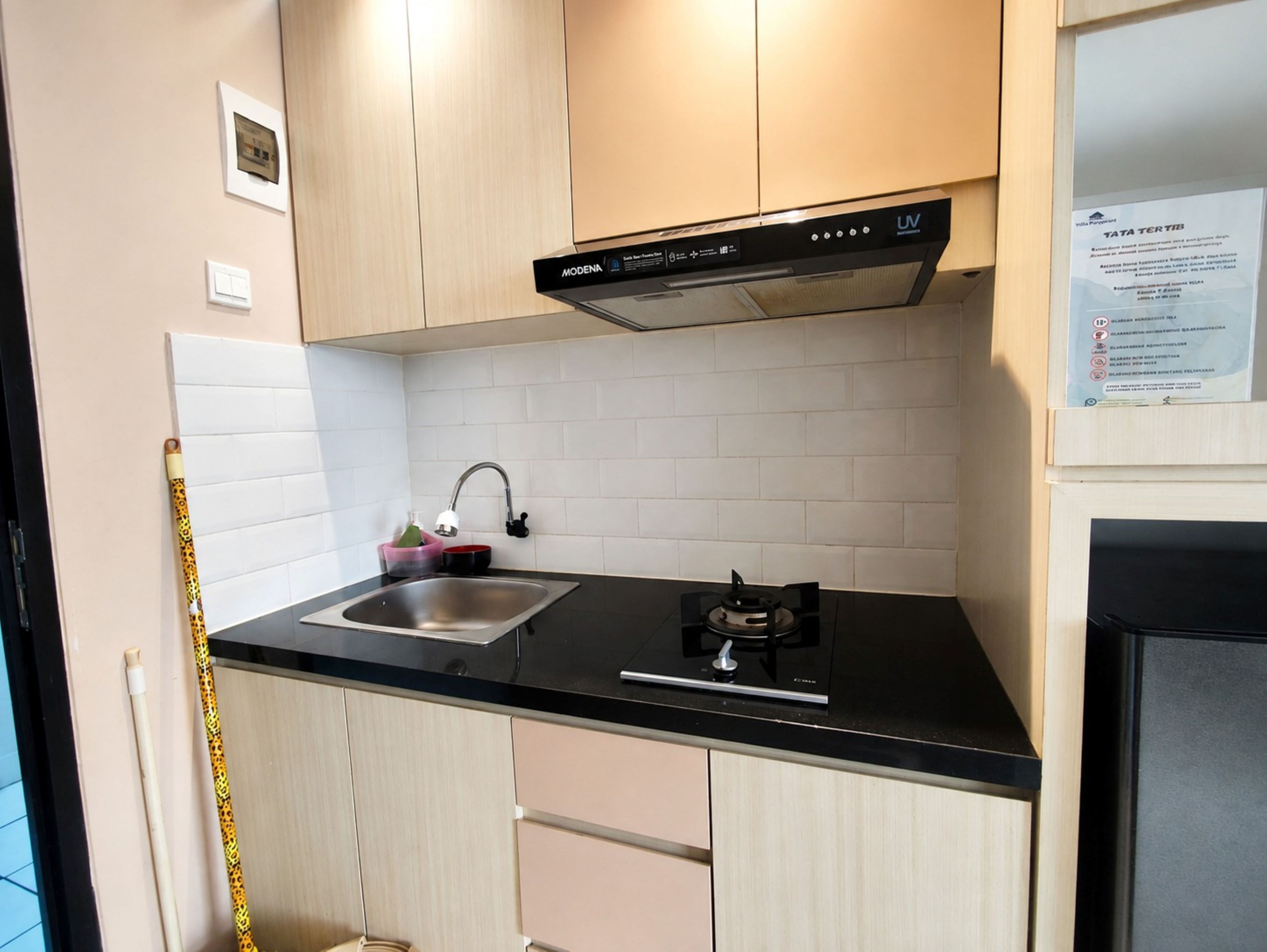 A kitchen with a black countertop, stainless steel sink, and a black range hood.