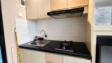 A kitchen with a black countertop, stainless steel sink, and a black range hood.