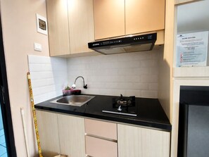 Una cocina con encimera negra, pileta de acero inoxidable y extractor de aire negro.