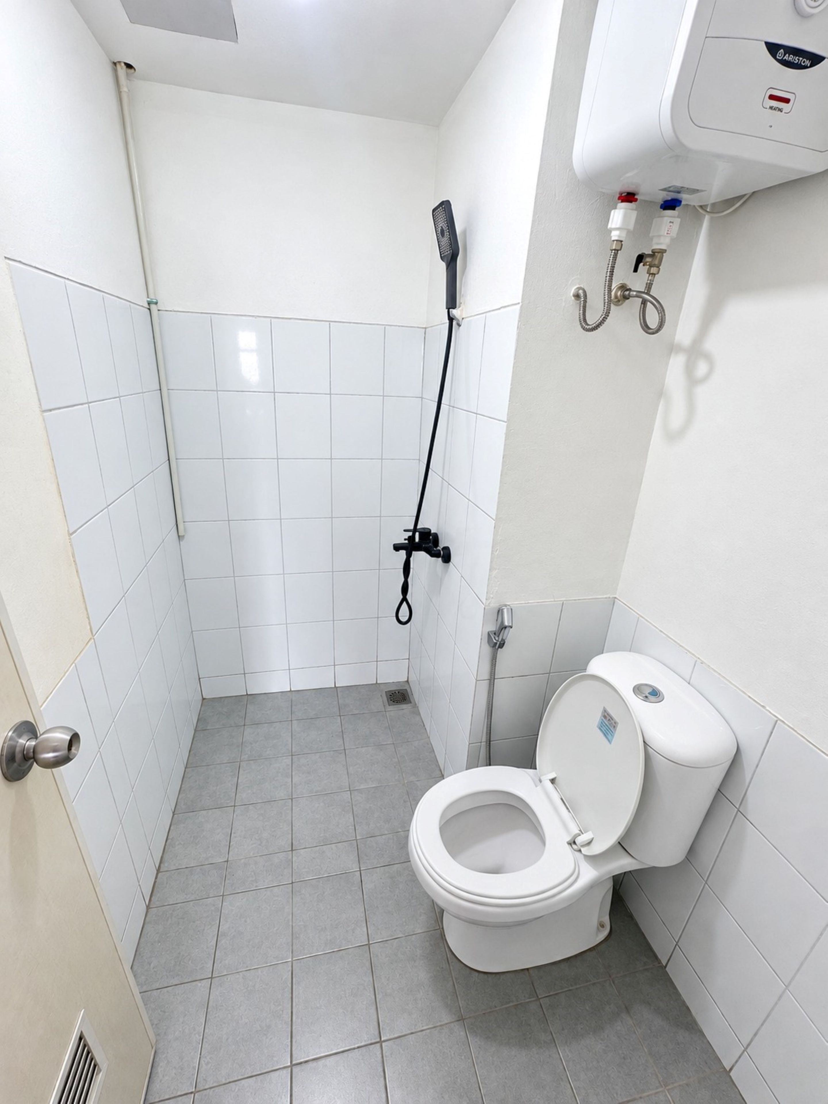 Un baño con inodoro, ducha y calentador de agua.