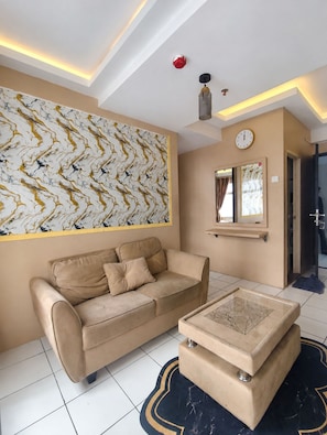 Una sala de estar moderna con un sofá color beige, una mesa de centro y un cuadro abstracto grande en la pared.