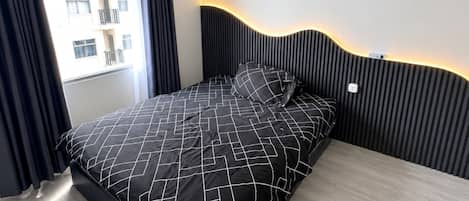 Quarto moderno com cama, janela com cortinas e vista para edifícios.