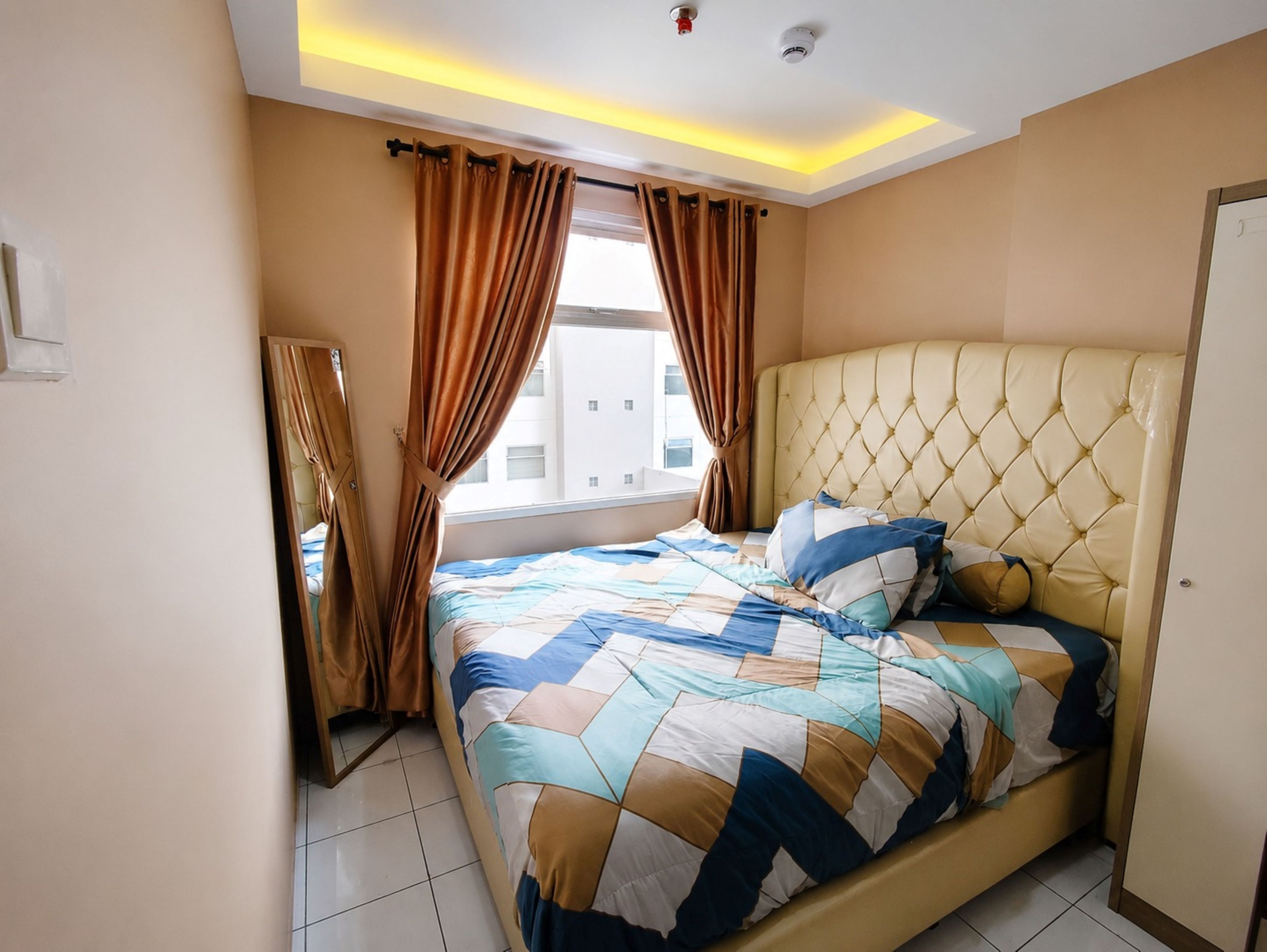 A bedroom with a bed, curtains, a headboard, and a window.