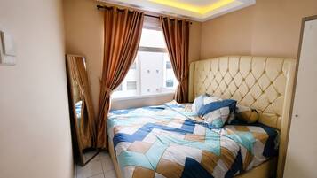 A bedroom with a bed, curtains, a headboard, and a window.