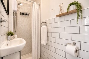 Ein Badezimmer mit Dusche, Waschbecken, Toilette und Toilettenpapierhalter.