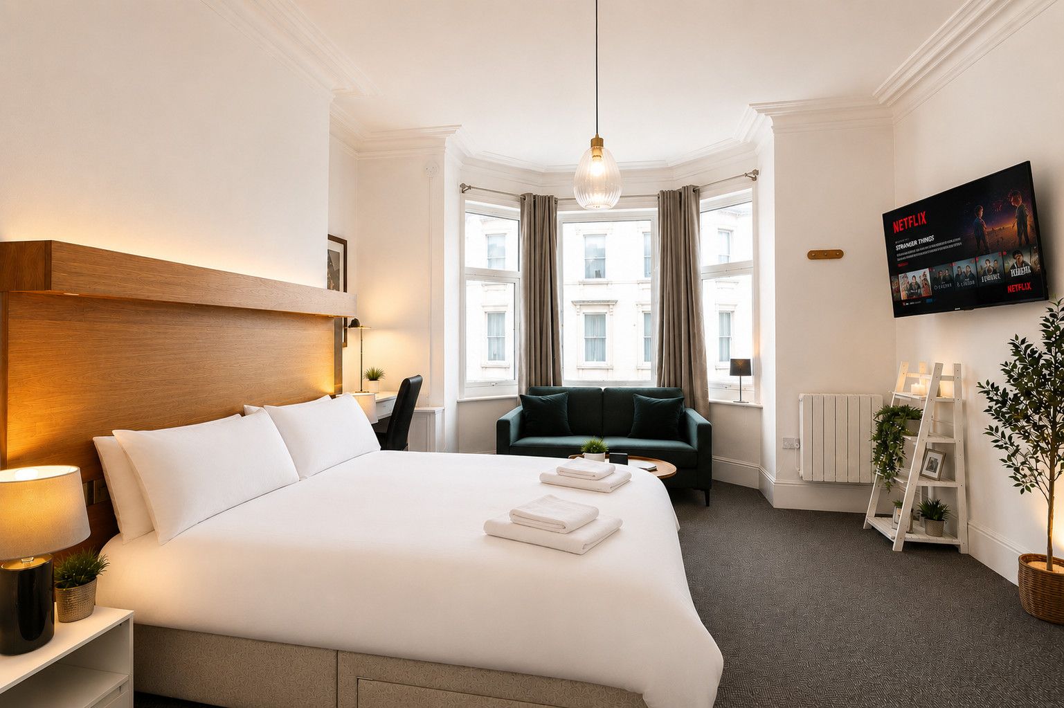 Habitación de hotel con una cama grande, un escritorio, un sofá, un televisor y una ventana con cortinas.
