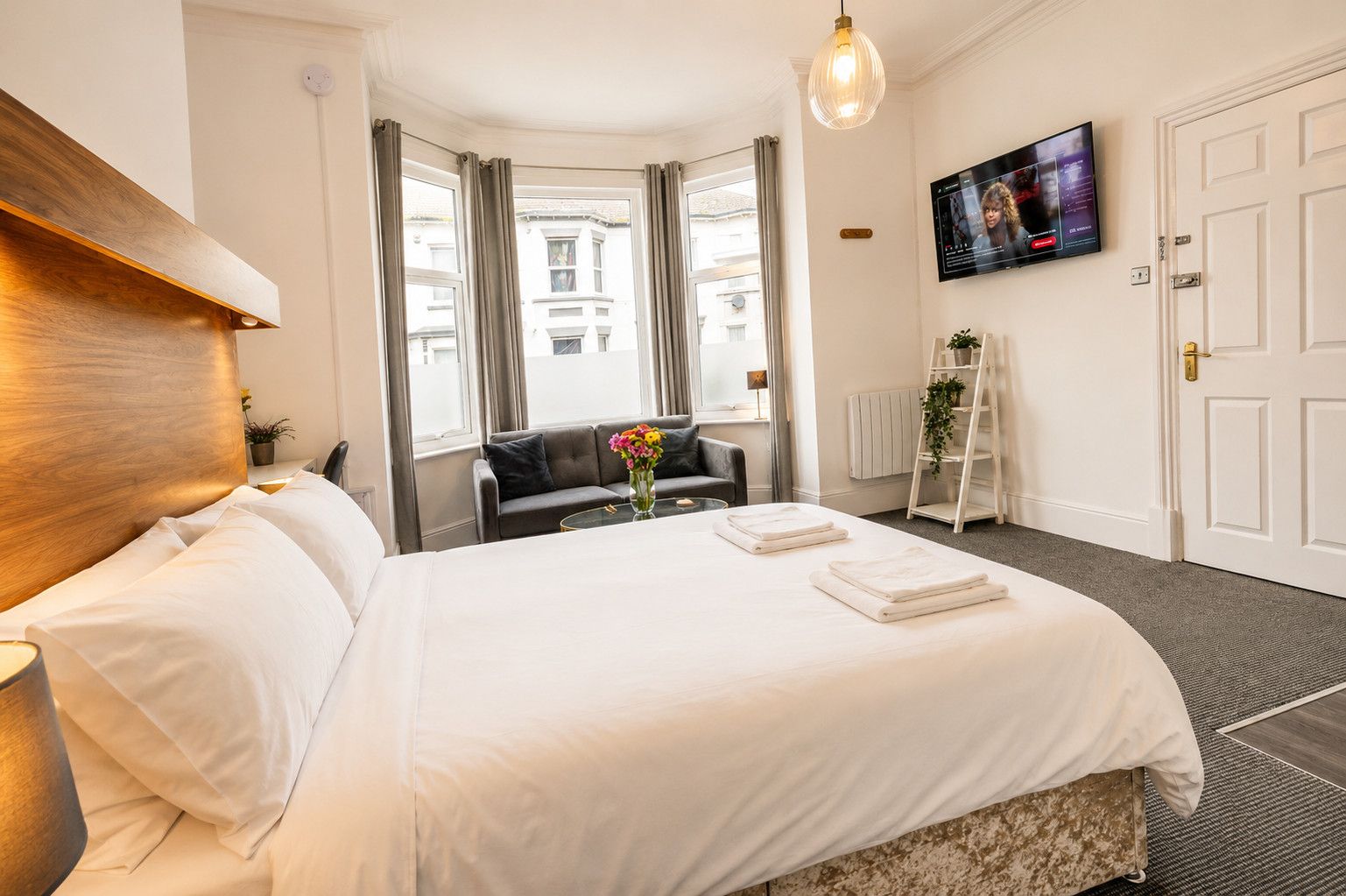 Une chambre d’hôtel avec un grand lit, une télévision, un canapé et une vue sur la ville.