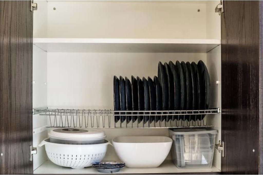 Un pensile da cucina con portabiancheria, colapasta, una ciotola e un contenitore di plastica.