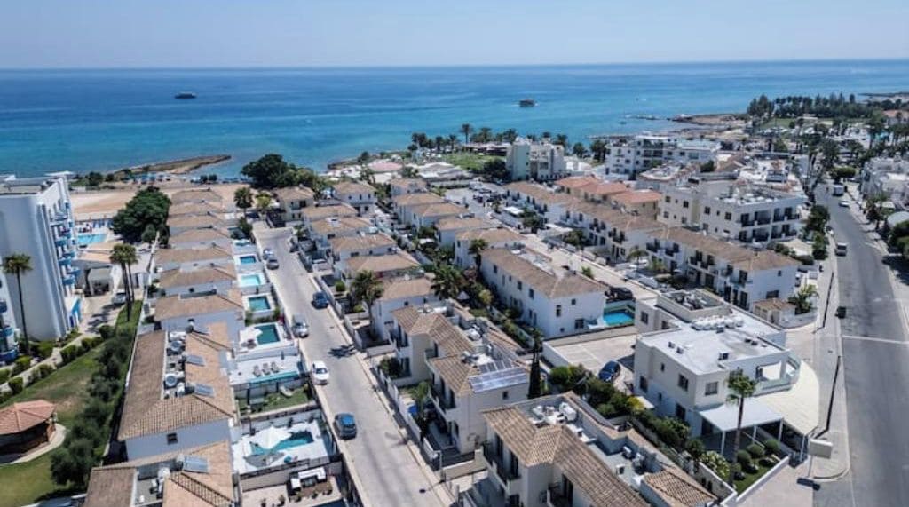 Un quartier résidentiel situé sur la côte, avec des immeubles à plusieurs étages, un ciel bleu dégagé et une vue sur la mer.