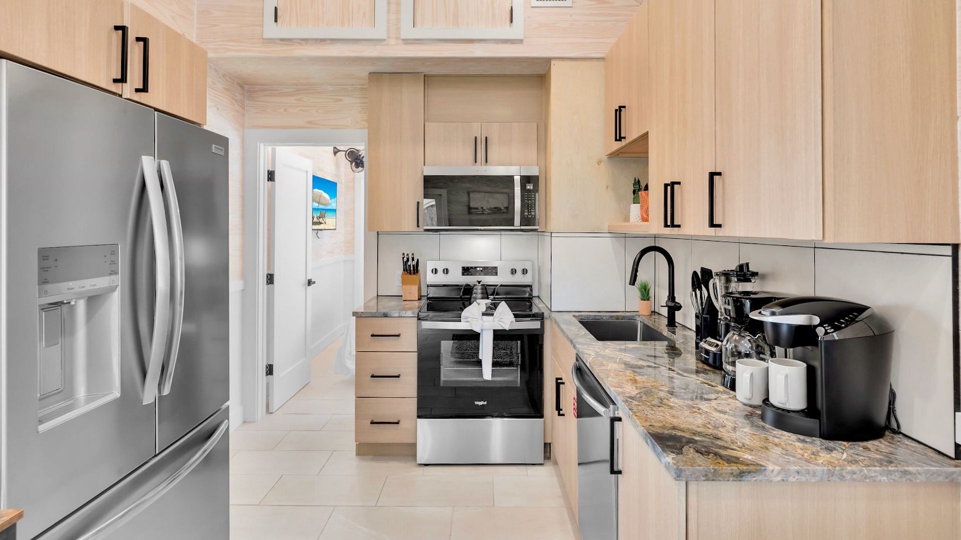 A modern kitchen with stainless steel appliances, wooden cabinets, and a marble countertop.