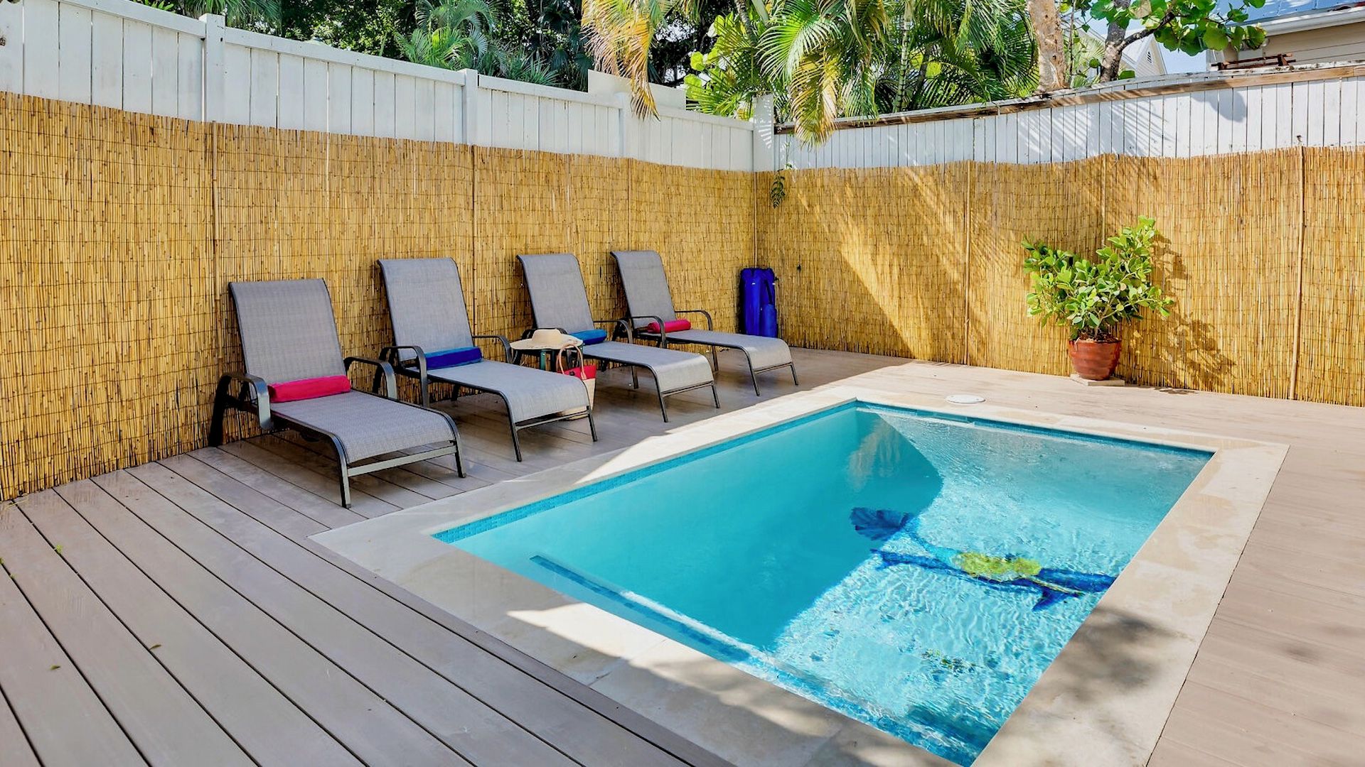 Una piscina rectangular amb una terrassa de fusta i gandules.