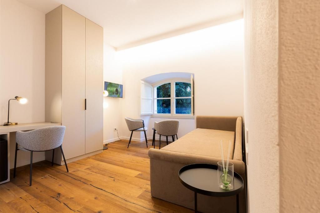 A compact room with a bed, a desk, two chairs, and a small table with a candle.