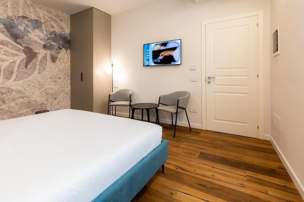 Quarto de hotel com cama, duas cadeiras, televisão e porta.