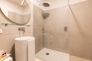 A modern bathroom with a glass-enclosed shower, a white sink, and a mirror above the sink. - KT exclusive hotel (Cagliari)