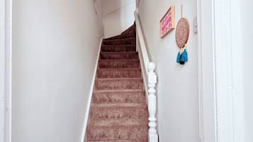 A staircase with a patterned carpet leading to a landing with a ceiling light fixture.