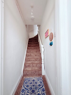 A staircase with a patterned carpet leading to a landing with a ceiling light fixture. - Stylish 7 person apartment close to Newcastle City Centre (Gateshead)