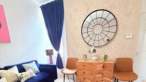 Uma sala de estar moderna com sofá, duas poltronas, mesa de centro e um objeto decorativo na parede.