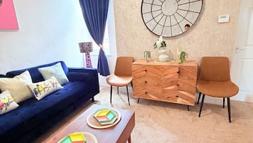 A modern living room with a sofa, two chairs, a coffee table, and a decorative wall piece.